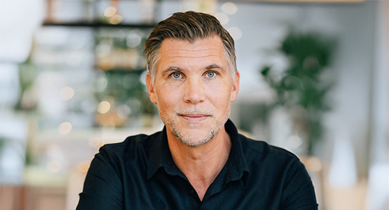 Porträtt av Peter Furby, talare på Frukost & AI-snack, sittande inomhus i ljus miljö och tittar in i kameran.