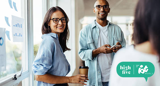 Business woman standing next to a window and having a meeting with her colleagues. Female sales executive working with her team in an office.