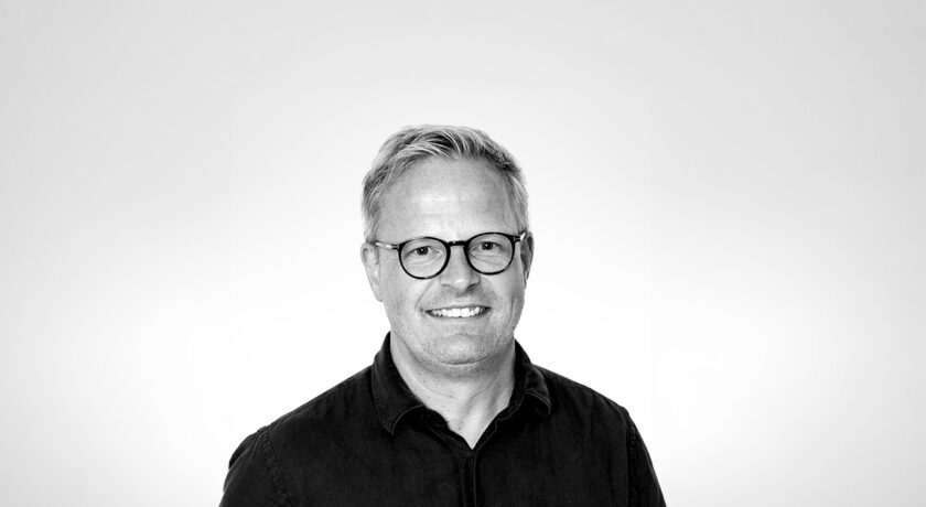 Man med glasögon som ler glatt, svart vit bild